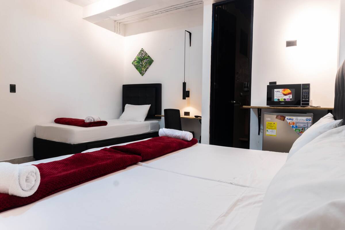 A hotel room with a bed, a bedside table, a microwave, and a wall-mounted artwork.