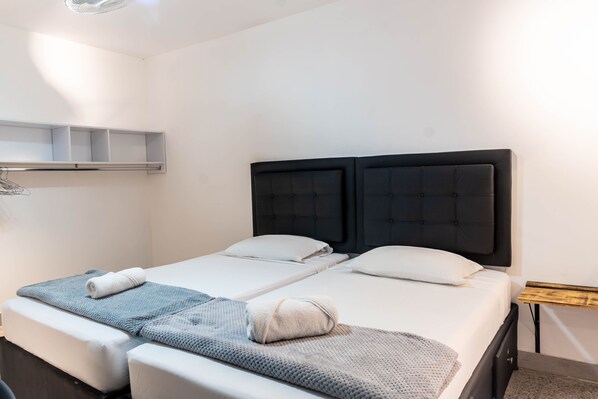 A double bed with a black headboard, a small bedside table, and a wall-mounted shelf. - hotel civitas medellin (Medellín)