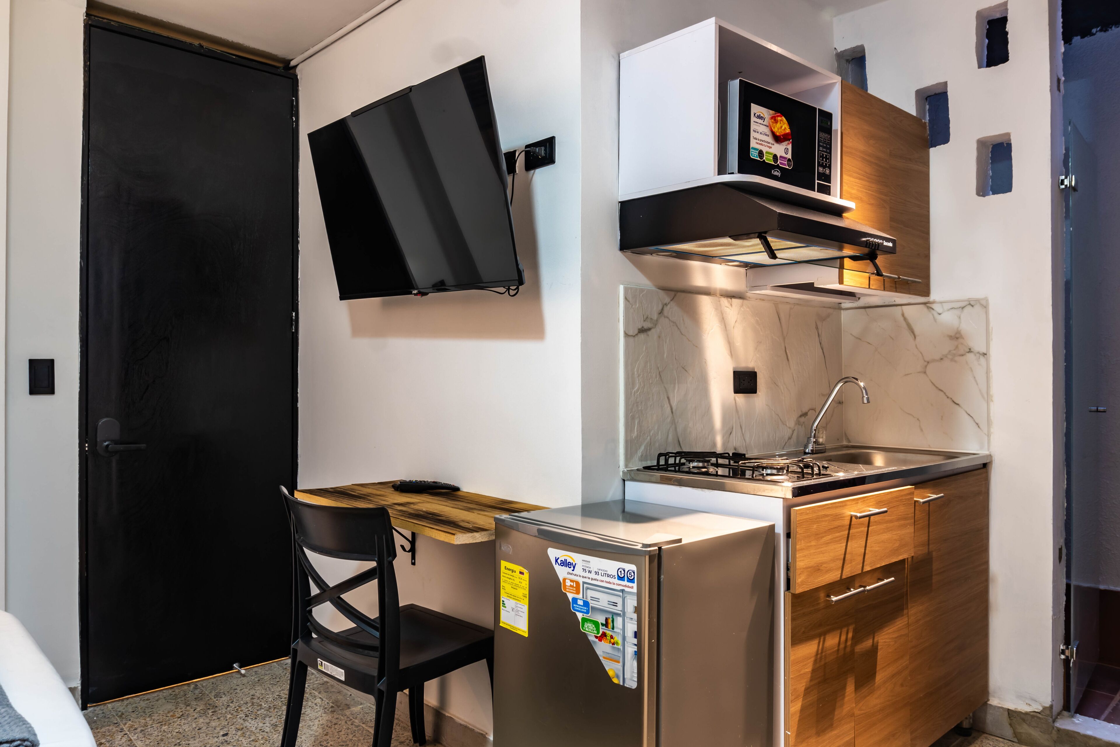 Une cuisine compacte équipée d’un réfrigérateur, d’une cuisinière et d’un four à micro-ondes.