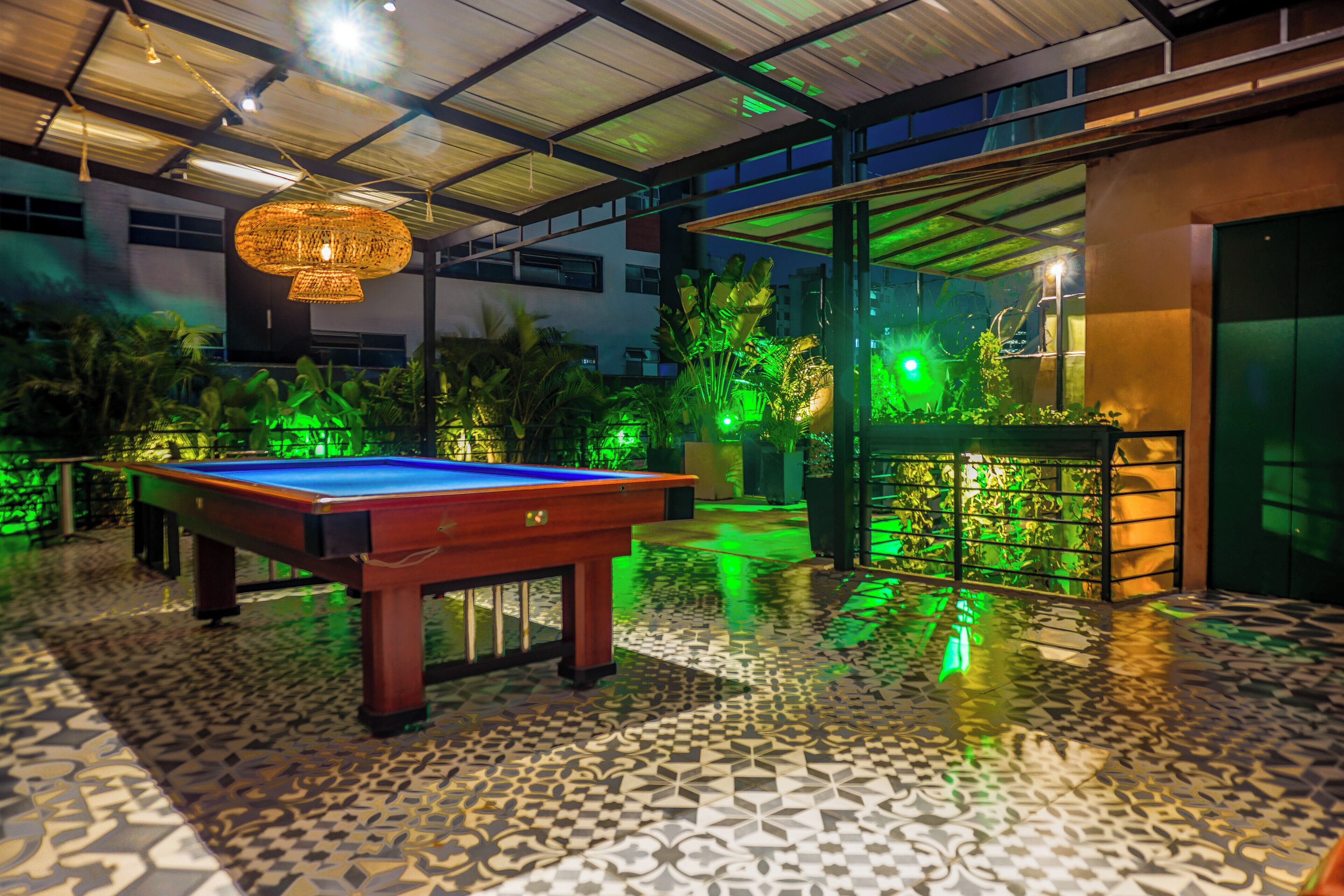 A pool table in a room with patterned flooring and a hanging light fixture.