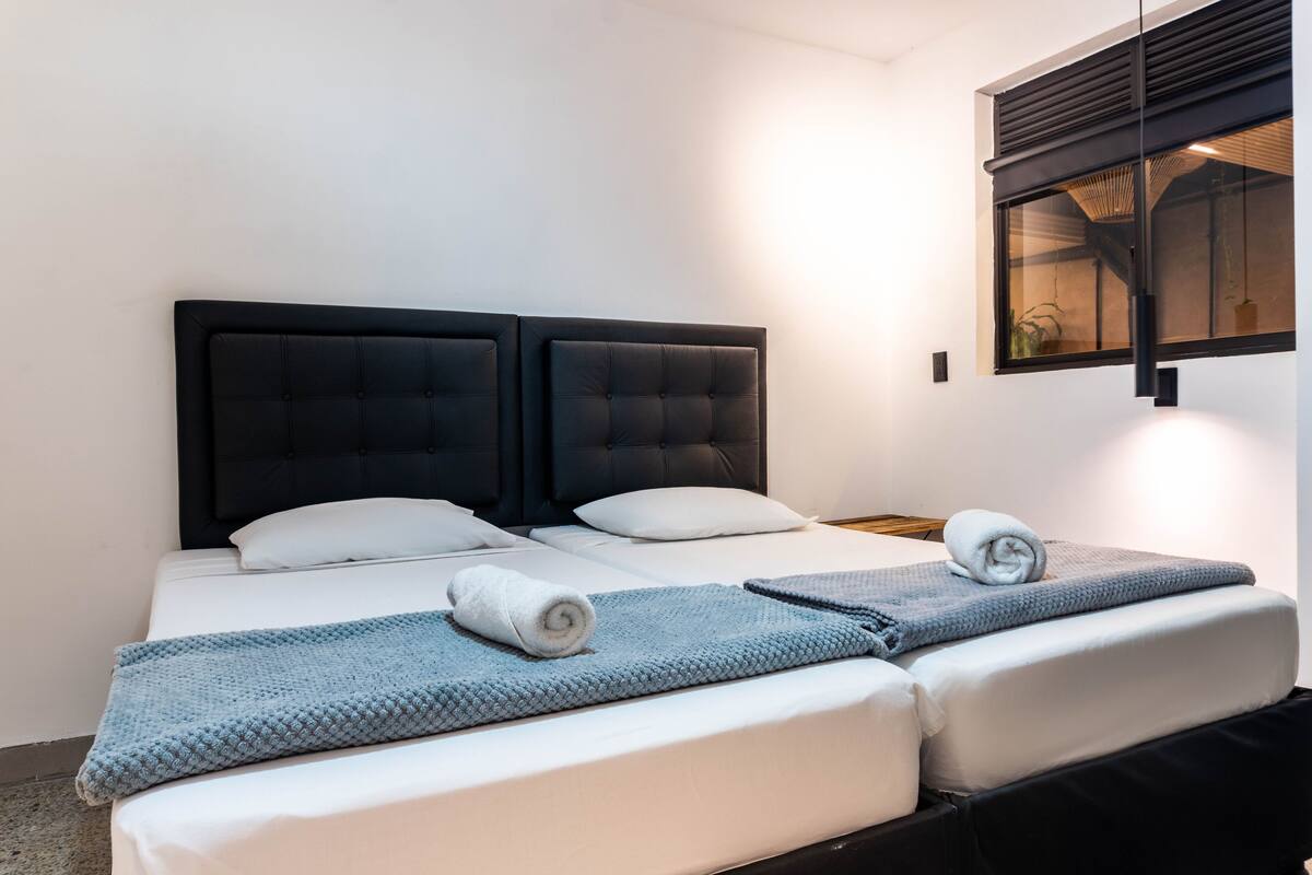 A double bed with a black headboard, white bedding, and a blue blanket.