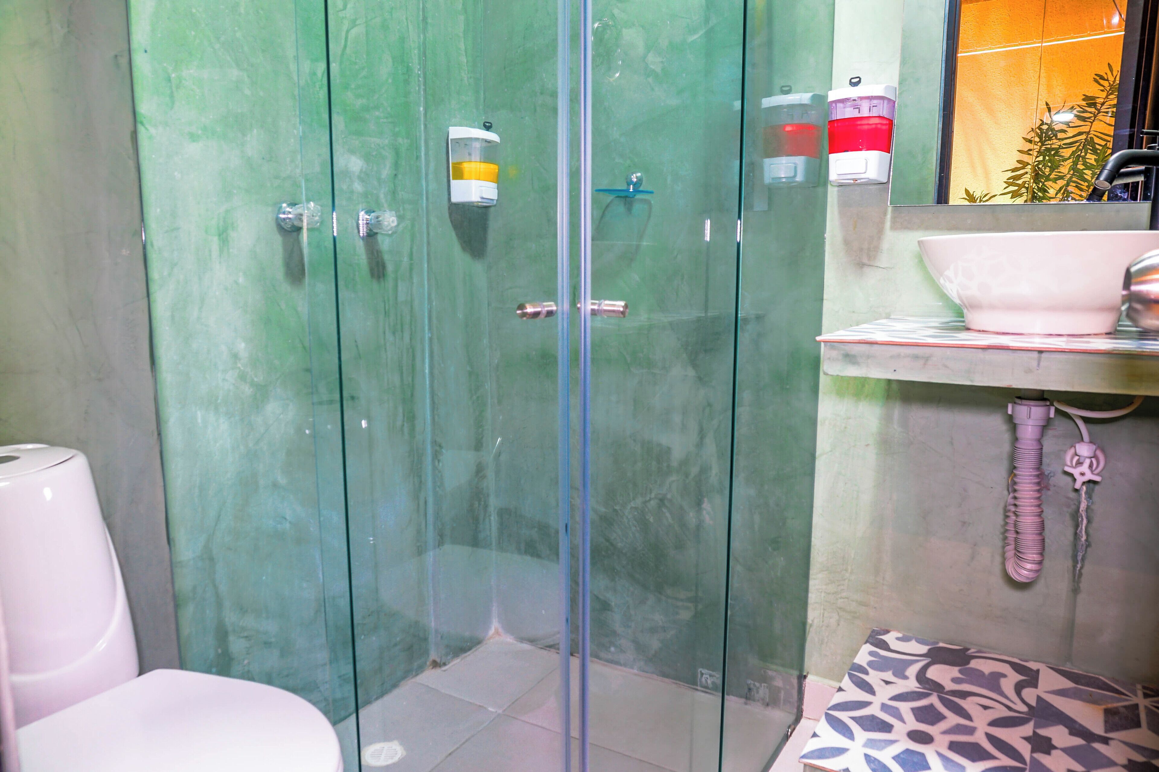 A bathroom with a glass shower enclosure, a sink with a mirror, and a toilet.