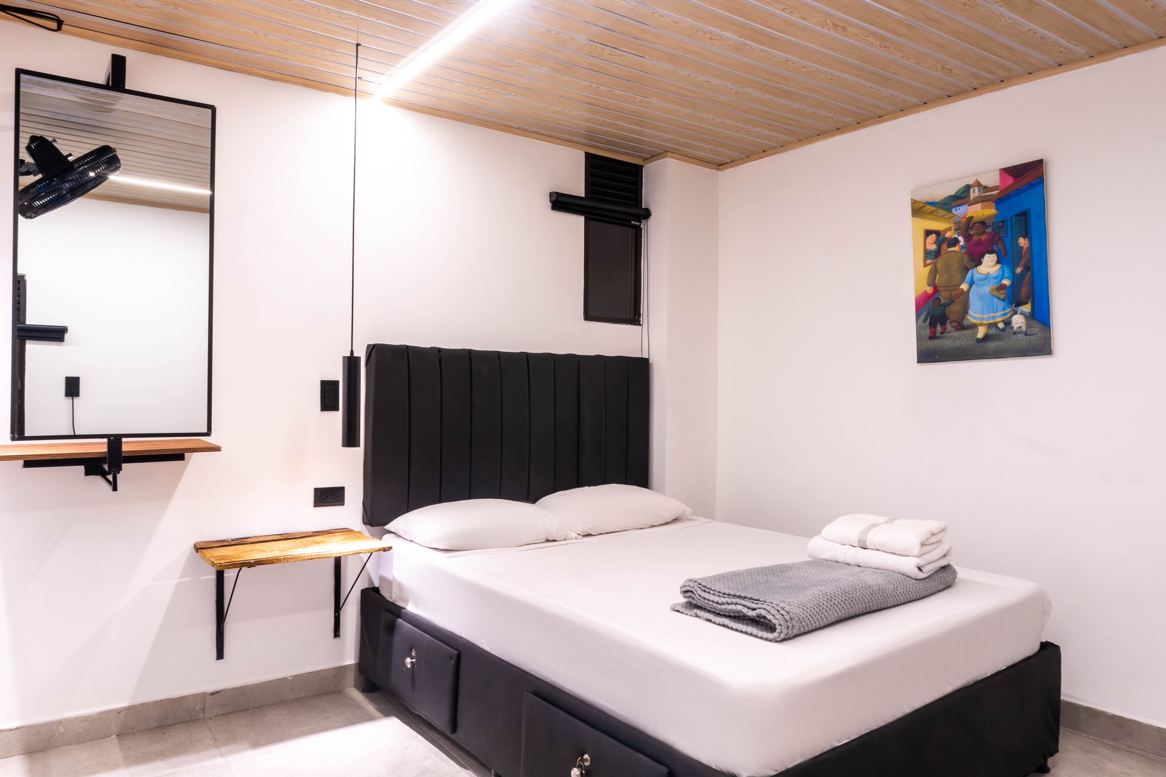 Un dormitorio moderno con una cama, mesita de noche y un cuadro en la pared.
