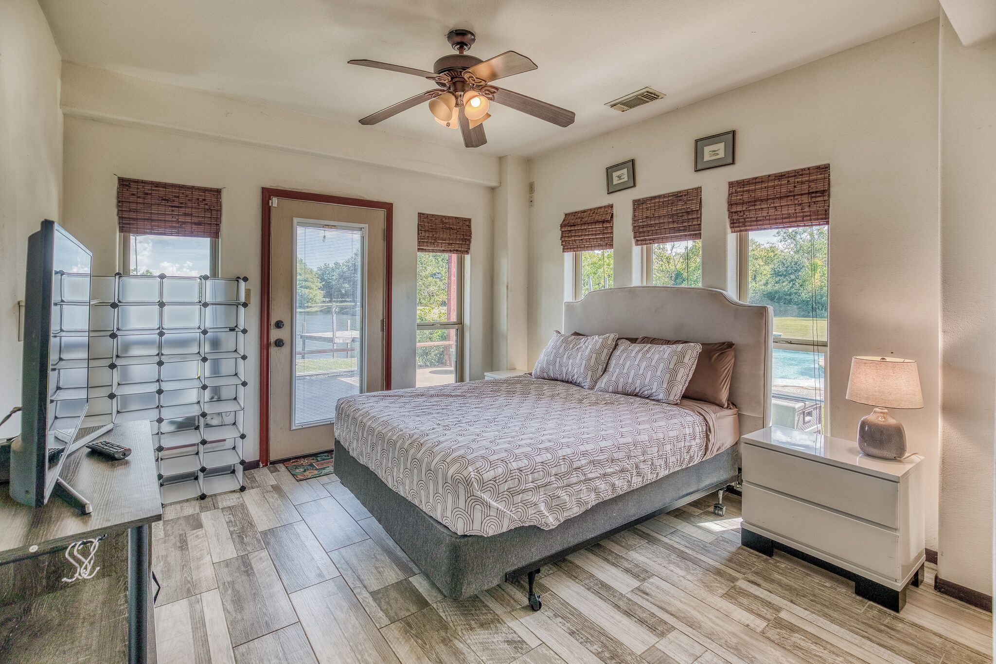A bedroom with a bed, bedside table, nightstand, and a ceiling fan.