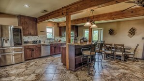 Una cocina amplia con armarios de madera, un refrigerador de acero inoxidable y una barra con taburetes.