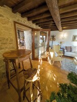 A rustic interior with a wooden table and chairs, stone walls, and a tiled floor.