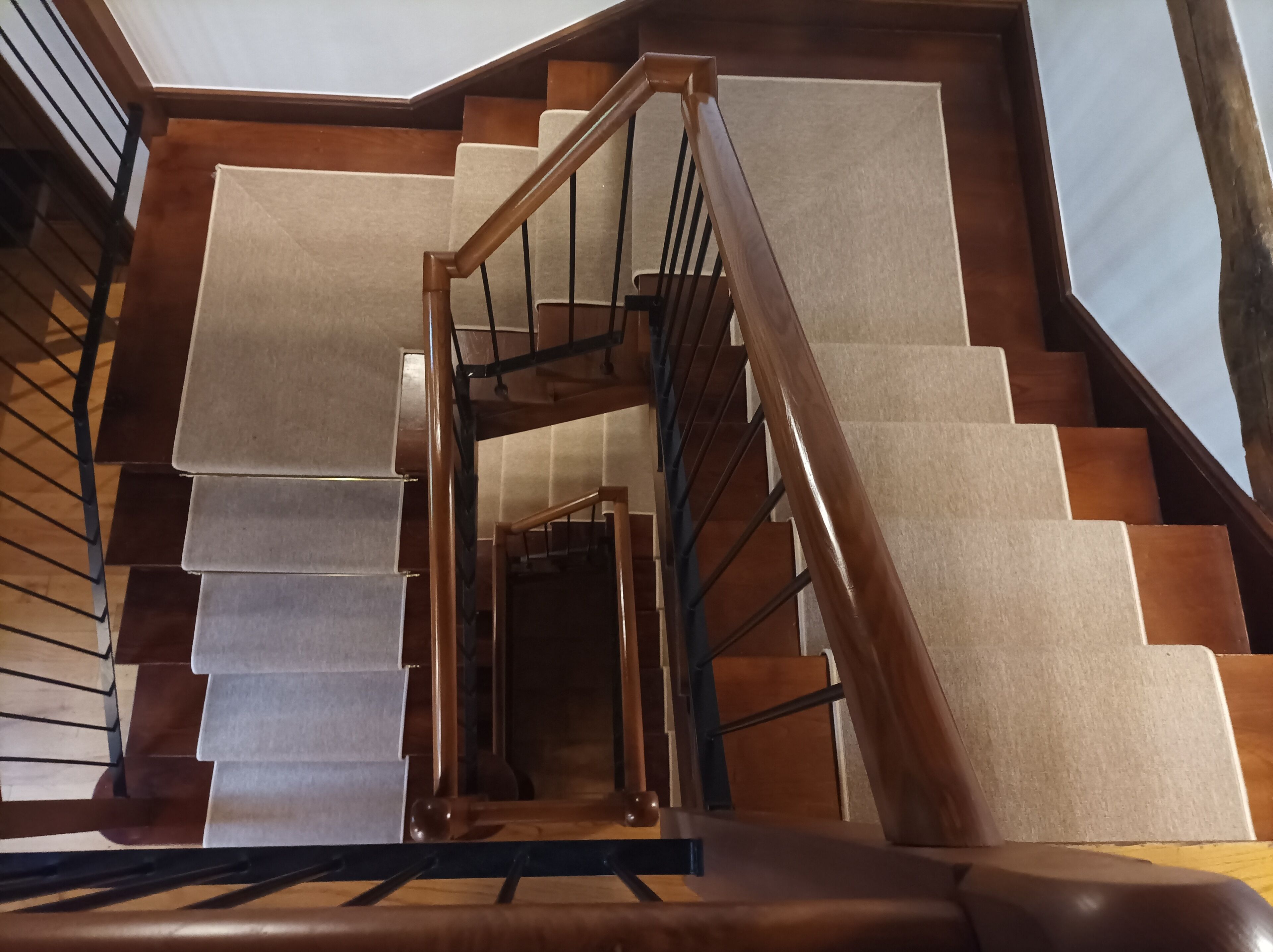 Eine Holztreppe mit Handlauf und Teppichstufen.