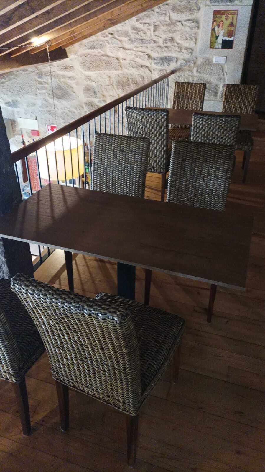 Et spiseområde med et langt bord og fletstole, en stenvæg og en trætrap.