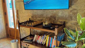 Una habitación acogedora con una estantería de madera, un tablero de ajedrez y un televisor que muestra una playa tropical.