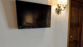 Ein Holztisch mit einem an der Wand montierten Fernseher, ein Stuhl und eine Wandlampe.