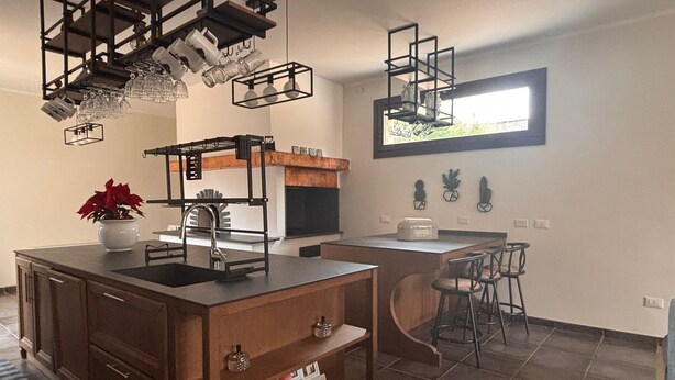 Une cuisine moderne dotée d’un îlot central, de tabourets de bar et de luminaires suspendus.