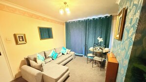 Ein Wohnzimmer mit einer Couch, einem Esstisch mit Stühlen, einer Chandelier und einer Wand mit Muster.