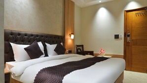 Quarto de hotel com uma cama grande, cabeceira de madeira e mesa de cabeceira com abajur.