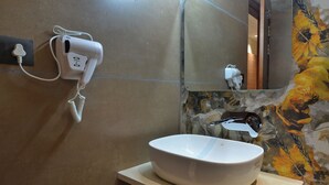 Casa de banho com uma pia branca, secador de cabelo e espelho.