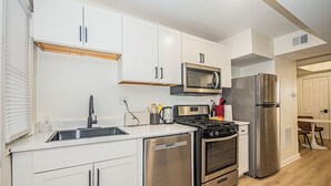 Eine moderne Küche mit weißen Schränken, Edelstahlgeräten und einer Holzausziehtafel.