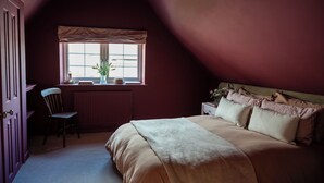 A bedroom with a large bed, a window with a view, a chair, and a radiator. - Boutique Cottage in the Heart of Kintbury. Pet friendly! (Kintbury)