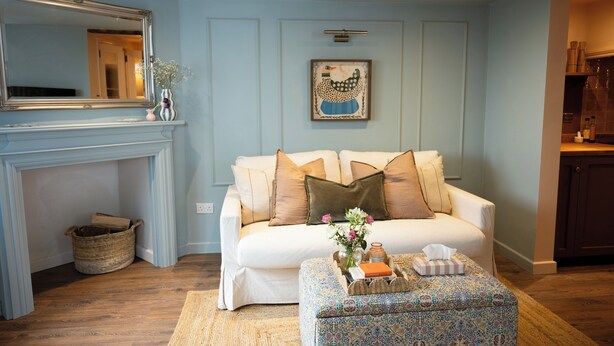 A living room with a white sofa, patterned ottoman, and a fireplace. - Boutique Cottage in the Heart of Kintbury. Pet friendly! (Kintbury)