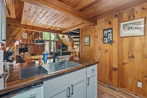 Ein Holzblockhaus-Interieur mit Küche, Essbereich und Kamin.