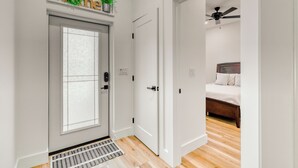 A modern home interior with a grey door, a small plant, and a bed with white bedding. - 3BR Boundary Breeze Heated Pool Beach Golf Nearby (Rotonda West)