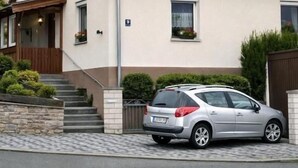 A two-story house with a red-tiled roof, a car parked in front, and a small garden area. - Corner Haus RM2 (Schnaittach)