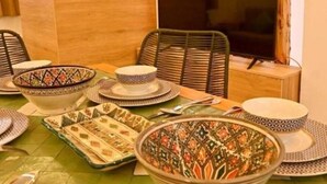 A dining area with a green tiled table, various patterned plates, and a television in the background. - Standard Double Room #1 (Tamraght Ouzdar)