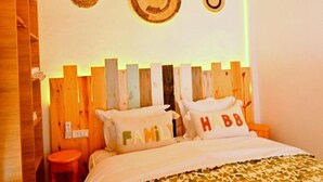 A bedroom with a wooden headboard, a bed with white bedding, and pillows with the word "FAMILY" and "HBB". - Standard Double Room #1 (Tamraght Ouzdar)