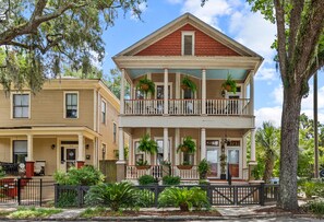 A two-story building with a balcony, columns, and potted plants. - The Majestic Fern (Savannah)