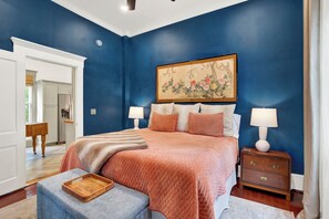A bedroom with a bed, bedside tables, a nightstand, and a painting on the wall. - The Majestic Fern (Savannah)