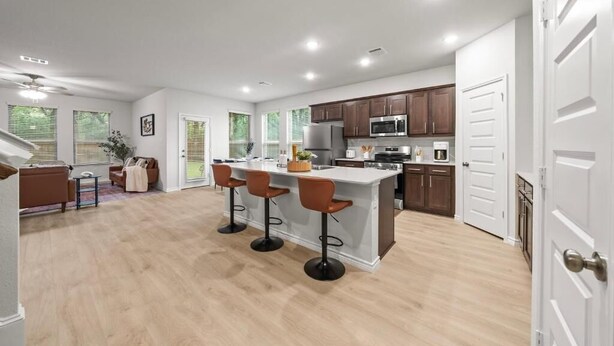 Een moderne keuken met een centraal eiland, barstoelen en een zithoek met een bank en stoelen.