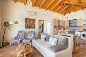 A cozy living room with a sofa, two armchairs, a wooden coffee table, and a hanging light fixture. - Villa Sol. Welcome to your dream getaway. Breathtaking views in quiet location. (Magganos)