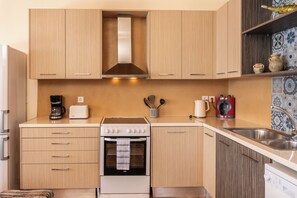 A kitchen with wooden cabinets, a stove, a coffee maker, and a sink. - Villa Sol. Welcome to your dream getaway. Breathtaking views in quiet location. (Magganos)