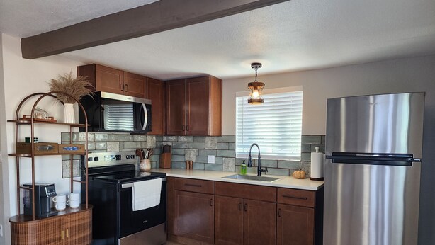 A modern kitchen with wooden cabinets, a stainless steel refrigerator, a built-in oven, and a microwave.