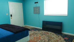 Une chambre à coucher avec un lit, une télévision, une porte et une fenêtre.