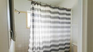 Une salle de bain avec un rideau de douche à rayures, des toilettes et des murs carrelés.
