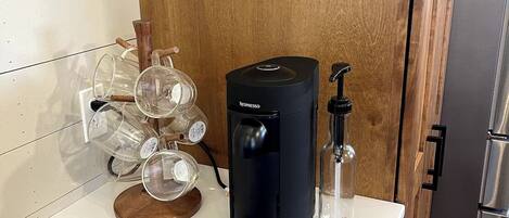 A kitchen counter with a coffee machine, a glass carafe, and a bottle of water.