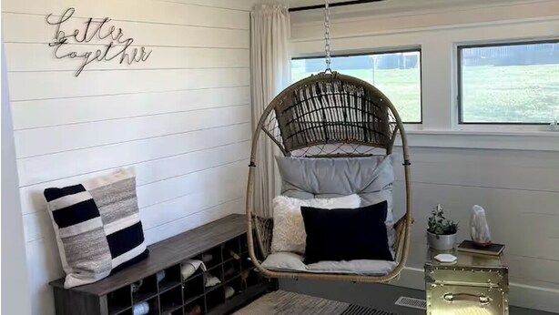 A cozy room with a hanging chair, a bench with cushions, a small side table, and a wall with a 'better together' sign. - Cozy 3-bedroom house with exquisite attention to detail! (Adair)