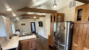 A modern kitchen with wooden cabinets, a stainless steel refrigerator, and a built-in island. - Cozy 3-bedroom house with exquisite attention to detail! (Adair)