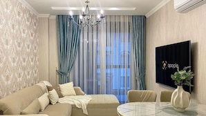 A modern living room with a beige sofa, a glass coffee table, and a TV mounted on the wall. - Аpartment 1+1 Qoople Triumph 17 next to Cleopatra Beach (Alanya)