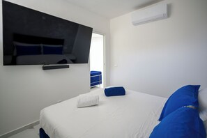 A hotel room with a bed, a flat-screen TV mounted on the wall, and a window.