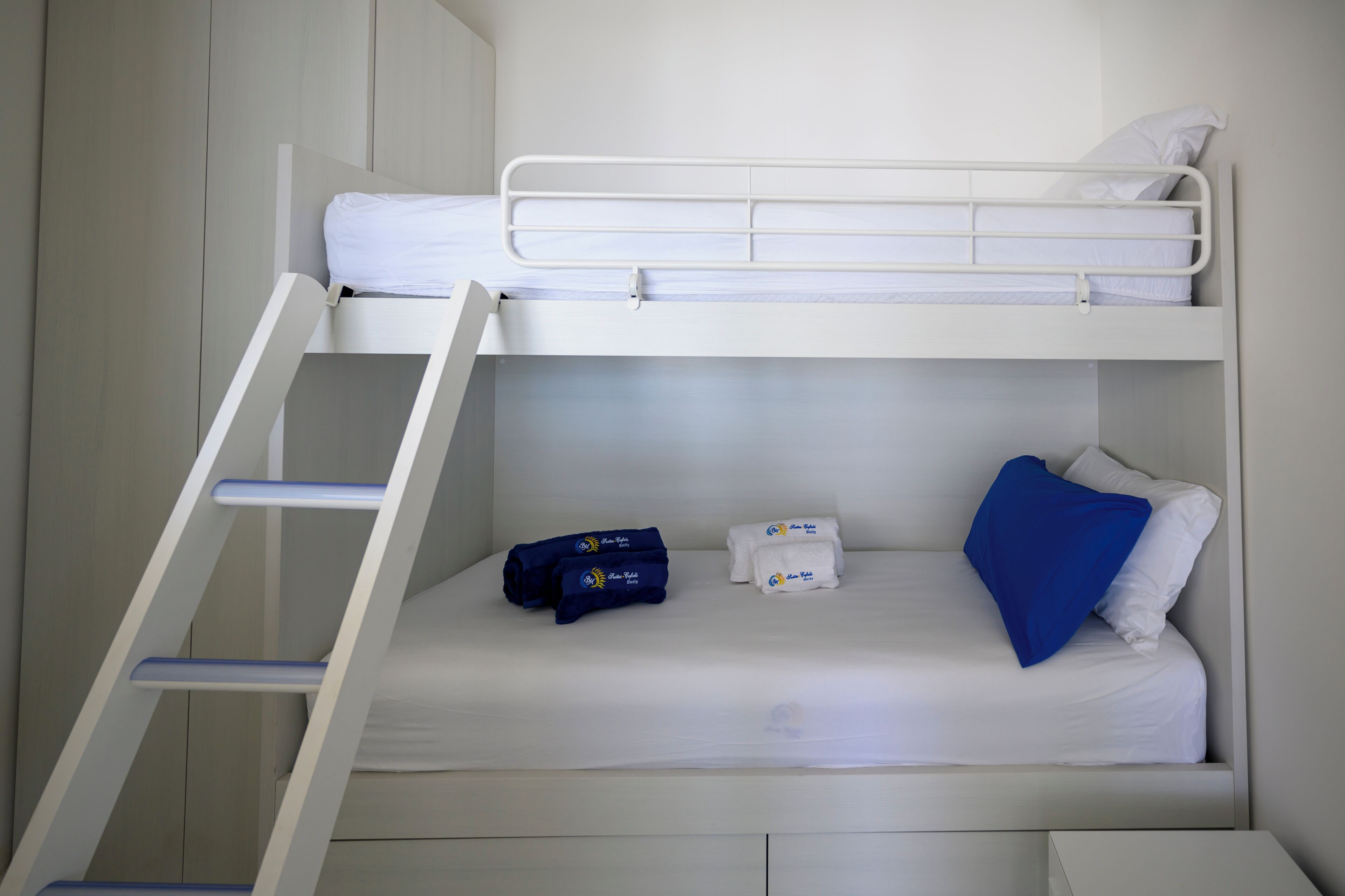 Habitación con literas, una mesita de noche pequeña y una almohada azul.