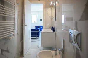 A modern bathroom with a white sink, mirror, and towel rack.
