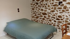 Una habitación pequeña con una cama, un escritorio y una silla. Las paredes tienen un diseño de piedra.