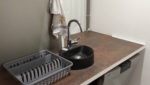 Una cocina con un lavaplatos, un escurreplatos, una toalla y un lavavajillas.