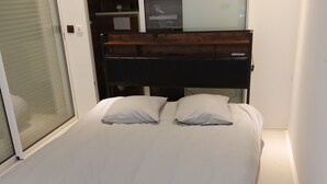 Un dormitorio con cama, puerta corrediza de vidrio y almacenamiento integrado.