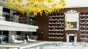 A modern lobby with a large yellow chandelier, marble flooring, white seating, and a bookshelf. - Luxe Brickell • 35th Floor • Skyline View • Free Spa & 5 Star Hotel Amenities (Miami)