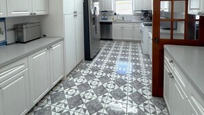 A kitchen with white cabinets, a tiled floor, a ceiling fan, and a refrigerator. - Villa Tequila - 6 bedrooms beach house (Nassau)