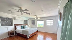 A bedroom with a bed, ceiling fan, and large windows. - Villa Tequila - 6 bedrooms beach house (Nassau)