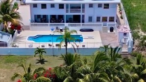 A large white building with a swimming pool, surrounded by palm trees and a sandy beach. - Villa Tequila - 6 bedrooms beach house (Nassau)
