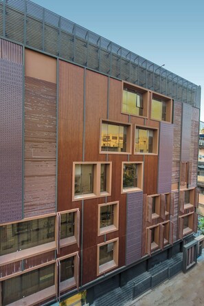 Un edificio moderno con varios balcones, ventanas amplias y techo de metal.
