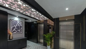 A modern interior with a patterned floor, a decorative ceiling, and a wall-mounted artwork. - Kzar Park (Kolkata)